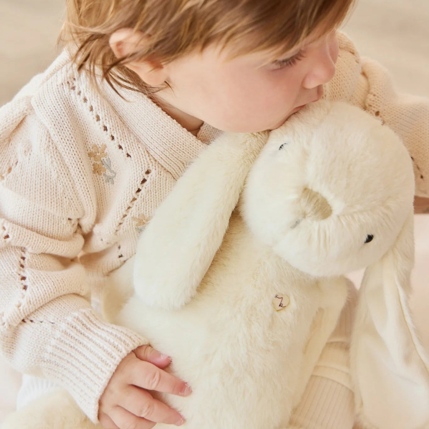 Child holding a plush rabbit toy in a cozy setting