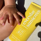 Yellow sunscreen bottle labeled 'everyday sunscreen' held by a child's hand.