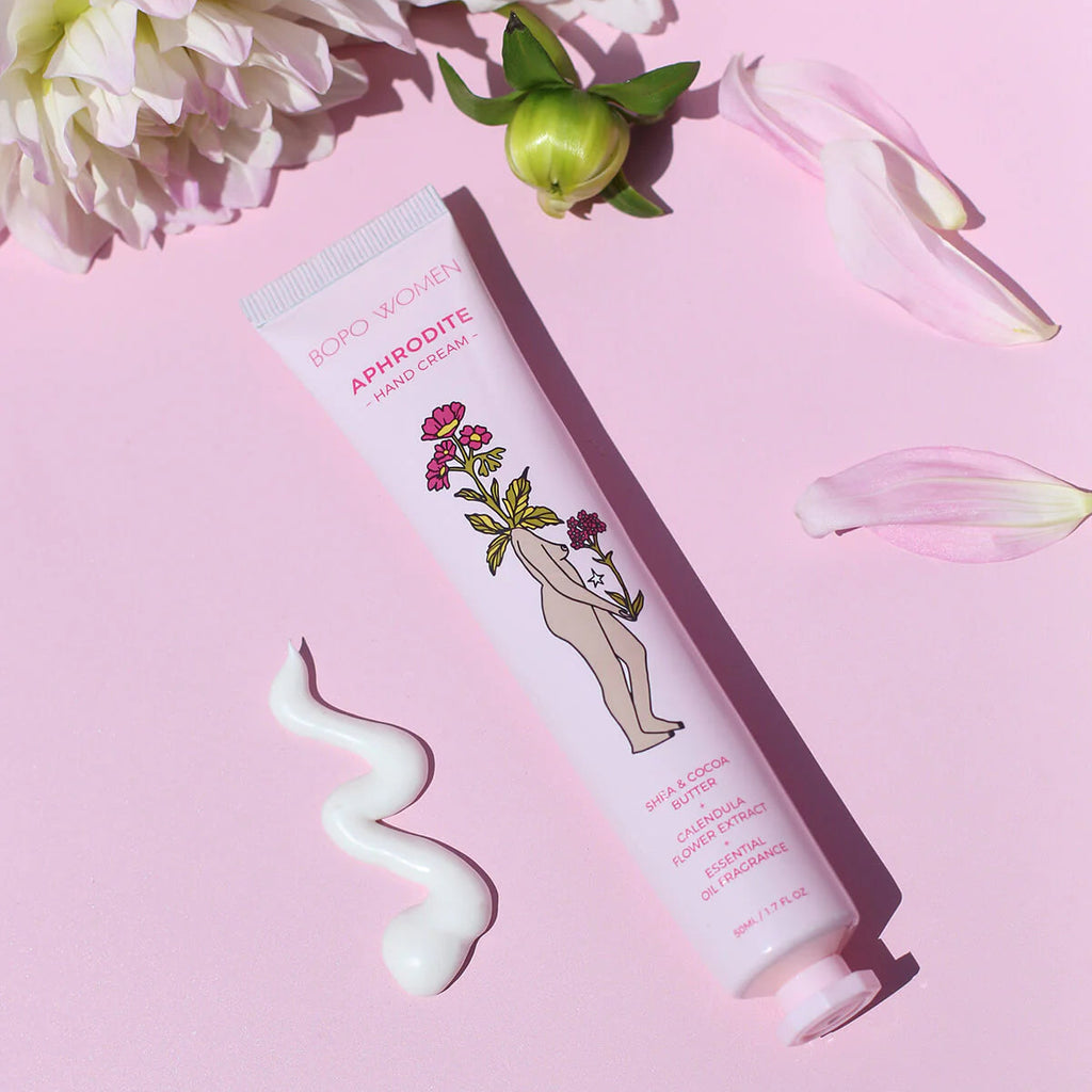 Hand cream tube with floral design on a pink background with flowers and petals.