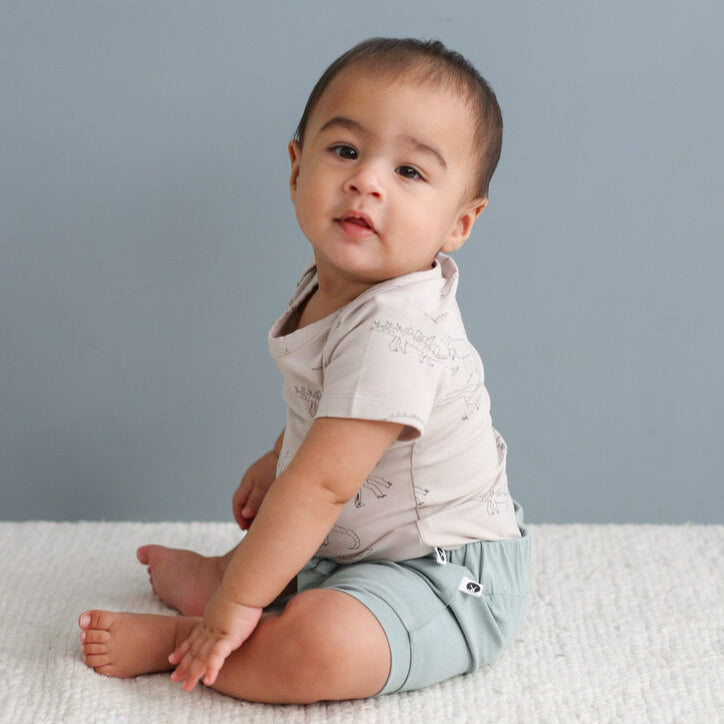 Baby sitting on a light gray surface with a plain background