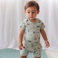 Child wearing a light blue outfit with nature-themed print on a white background