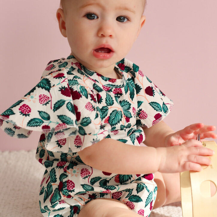 Baby wearing a floral outfit against a pink background
