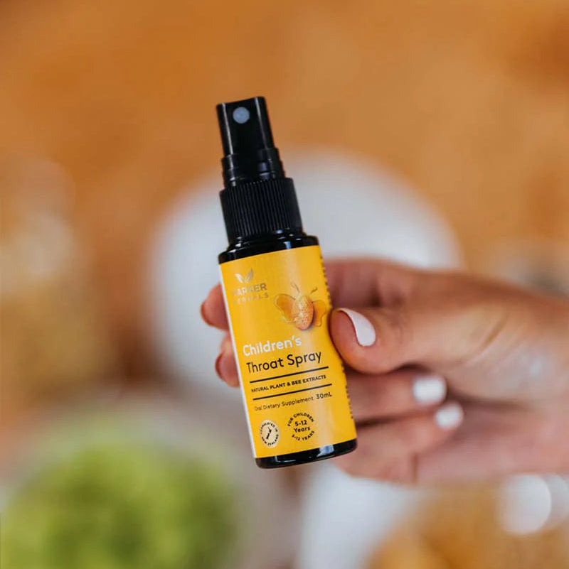Hand holding a bottle of 'Children's Throat Spray' with a blurred background