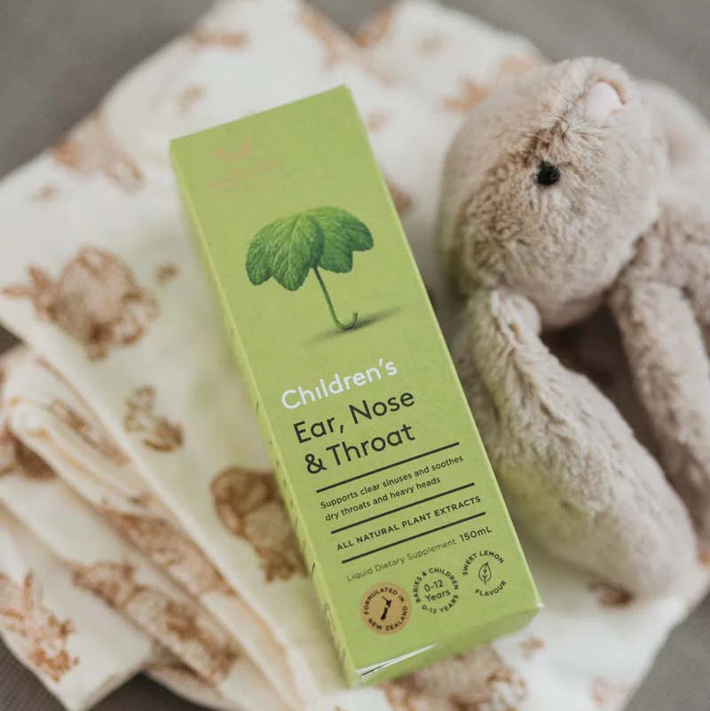 Green children's ear, nose, and throat supplement box on a soft fabric background with a teddy bear.