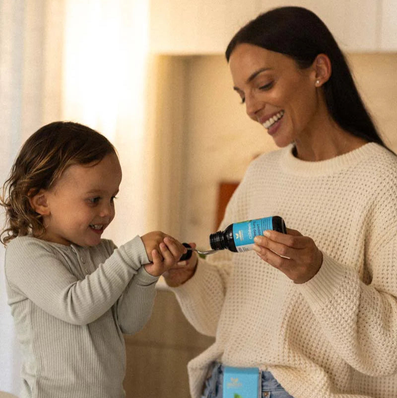 Woman giving child deep lung support syrup for cough.