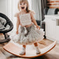 Child standing on a wooden balance board in a home setting