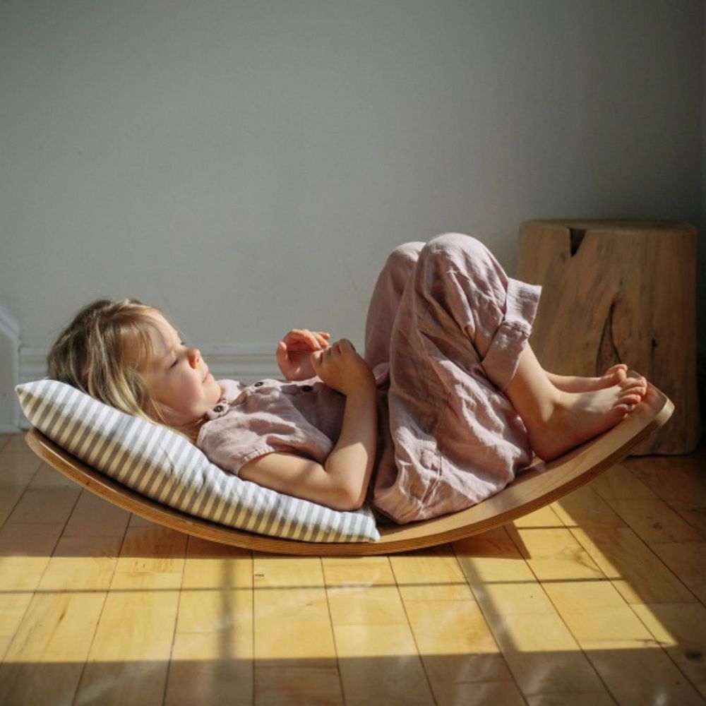Child lying on a wooden wave chair with sunlight casting shadows