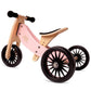 Pink and wooden balance bike with black wheels on a white background