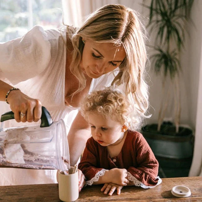 mum pouring smoothie mixture into child's cup
